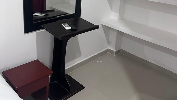 A room with a black vanity, a mirror, a small red side table, and white shelves. - Hotel Casa Evan (Mompos)