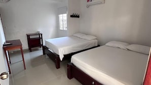 A room with two beds, a small table, a fan, and a window. - Hotel Casa Evan (Mompos)