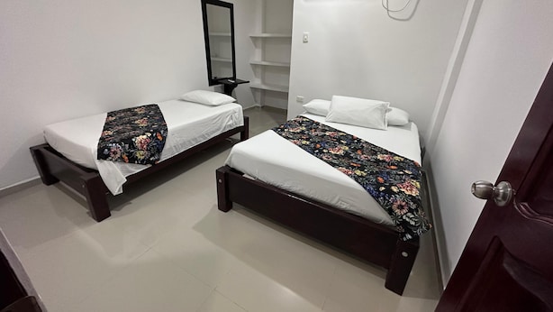 A room with two single beds, a mirror, an air conditioning unit, and a door. - Hotel Casa Evan (Mompos)