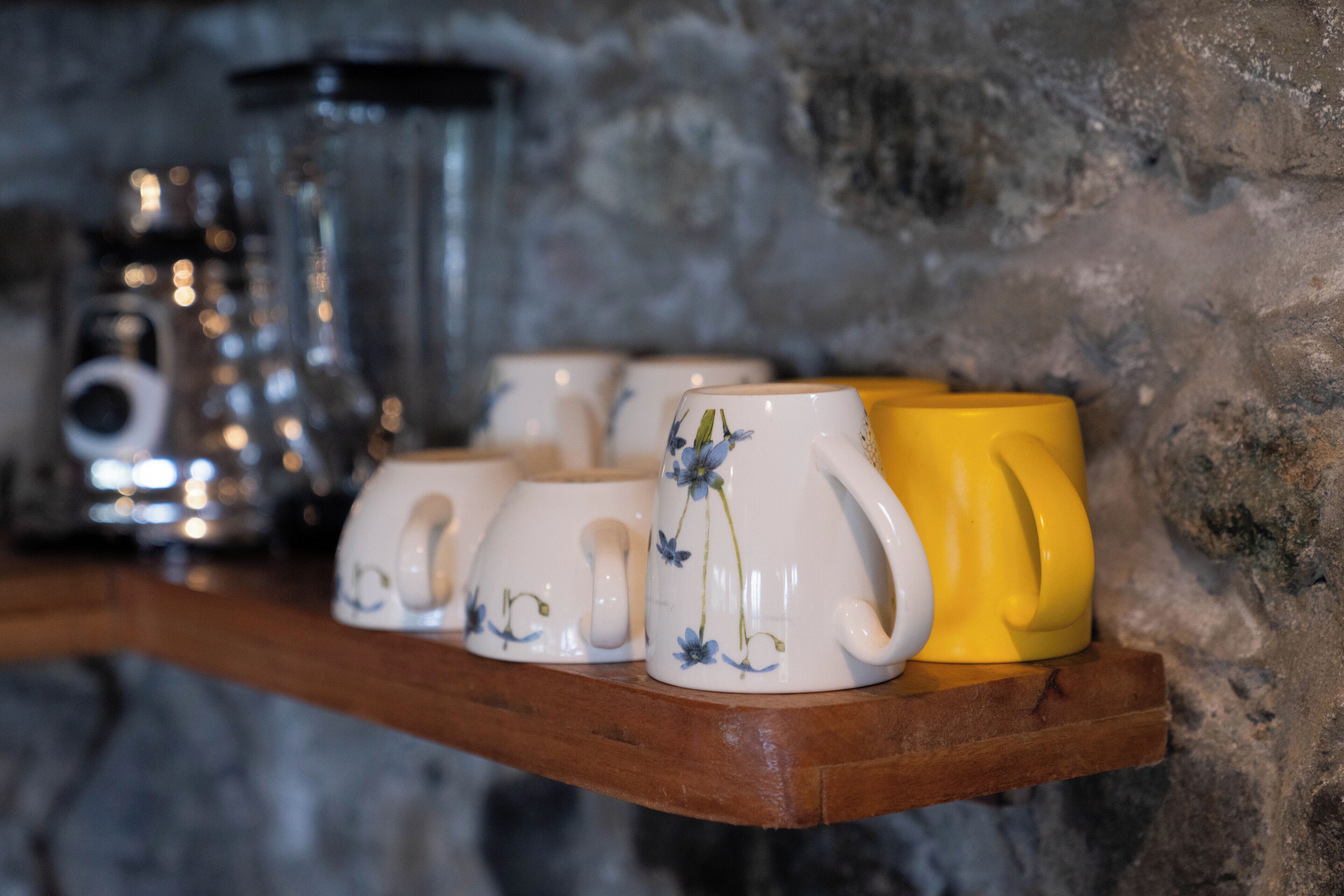 A shelf with ceramic mugs and a teapot.