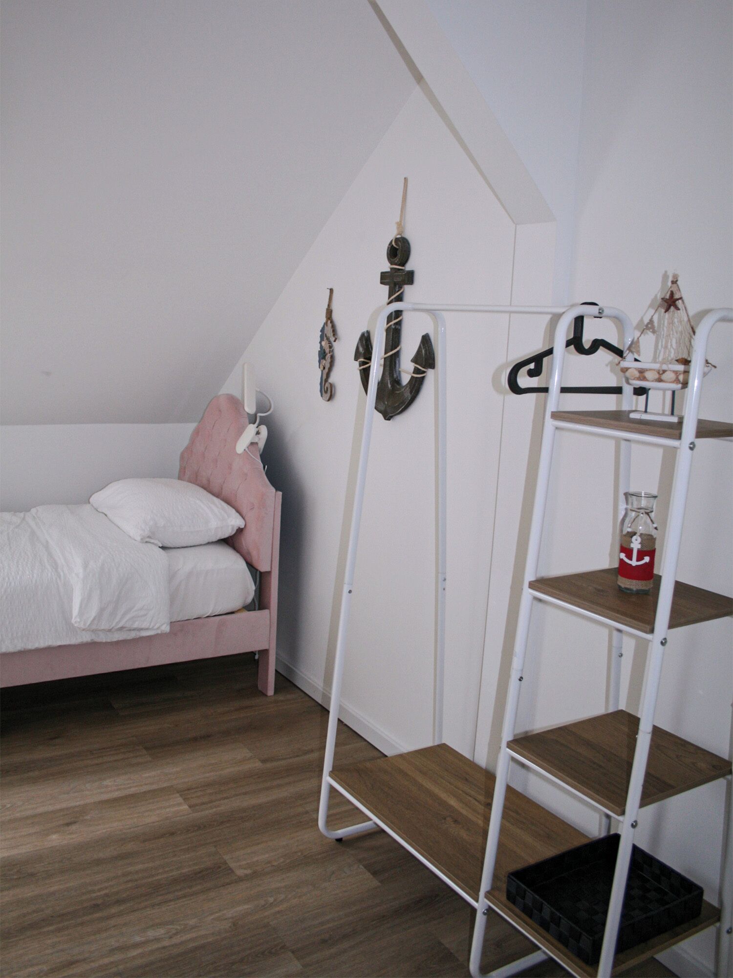 Un dormitorio con una cama litera, una pequeña mesa de madera y un estante de metal blanco adosado a la pared.