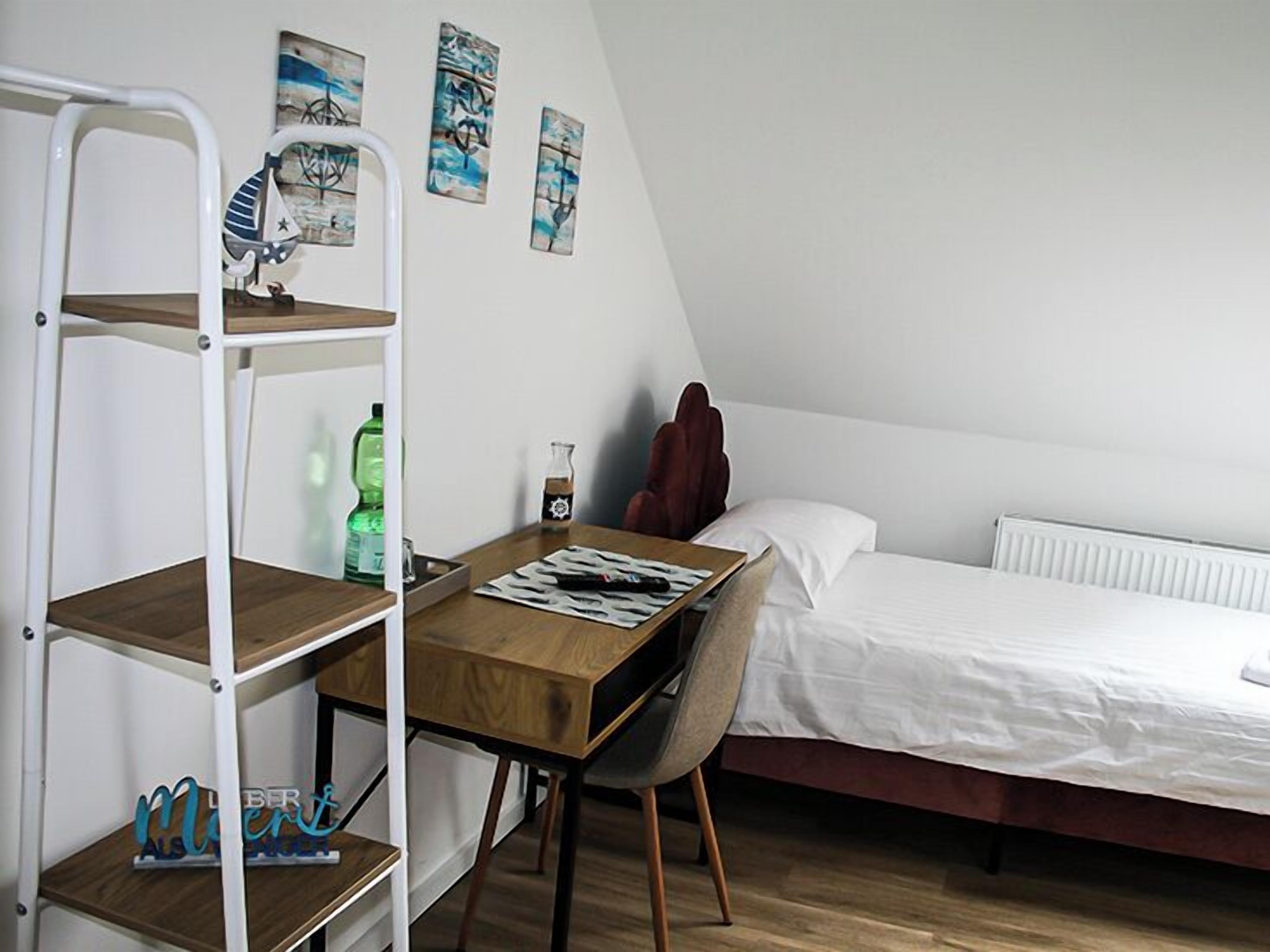 Een slaapkamer met een stapelbed, een bureau met stoel, een radiator en kunst aan de muur.