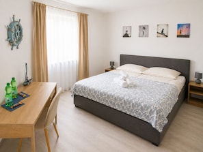 Ett hotellrum med en säng, ett skrivbord, en stol, en dekorativ skeppsratt och tre tavlor på väggen.
