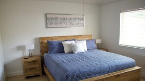 A bedroom with a wooden bed, a nightstand with a lamp, and a window with blinds. - Family-Friendly Home at the Heart of DFW- close to all popular attrations! (Euless)