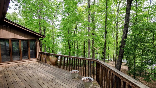 A wooden deck with a railing, large windows, and two planters. - Cozy and serene fishing cabin, Family Traditions,  private dock and lake views. (Gainesville)