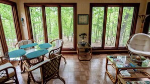 A room with large windows, wicker furniture, and a glass coffee table. - Cozy and serene fishing cabin, Family Traditions,  private dock and lake views. (Gainesville)