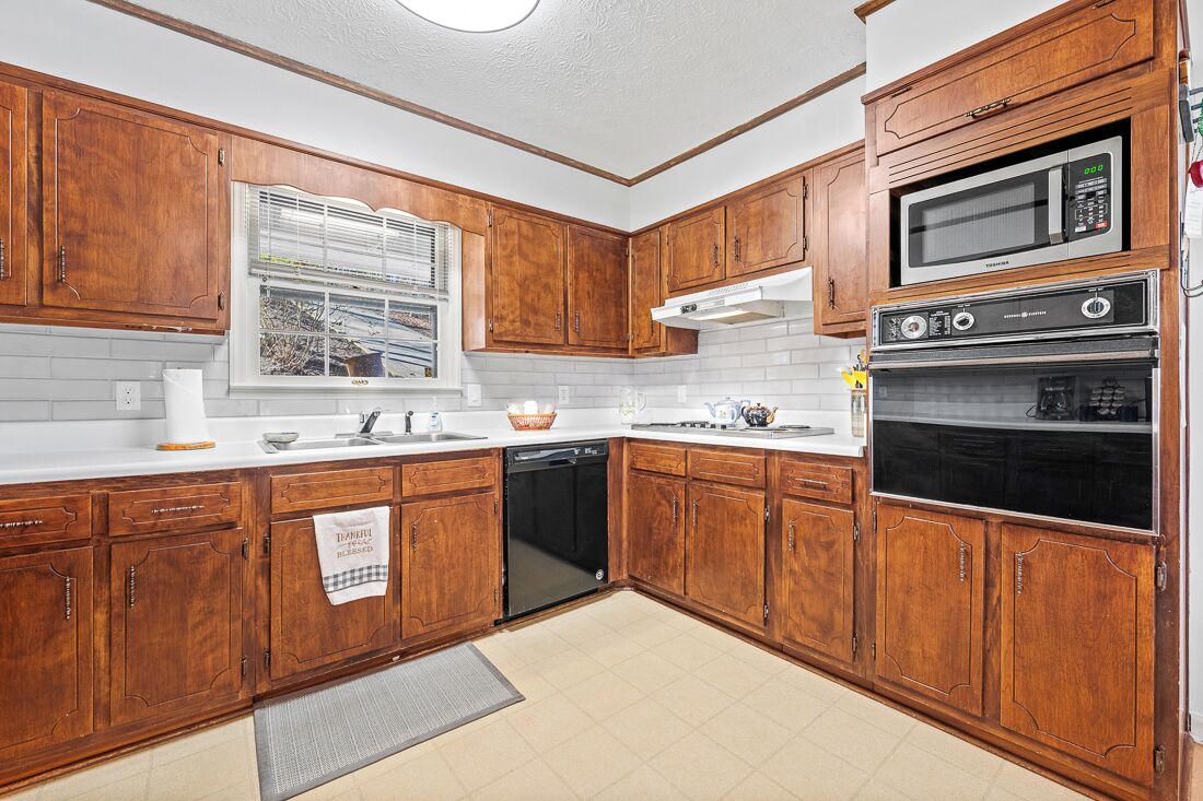 A kitchen with wooden cabinets, a built-in microwave, a double oven, and a dishwasher.