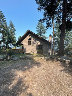 A small wooden cabin with a sloped roof, a chimney, and a window.