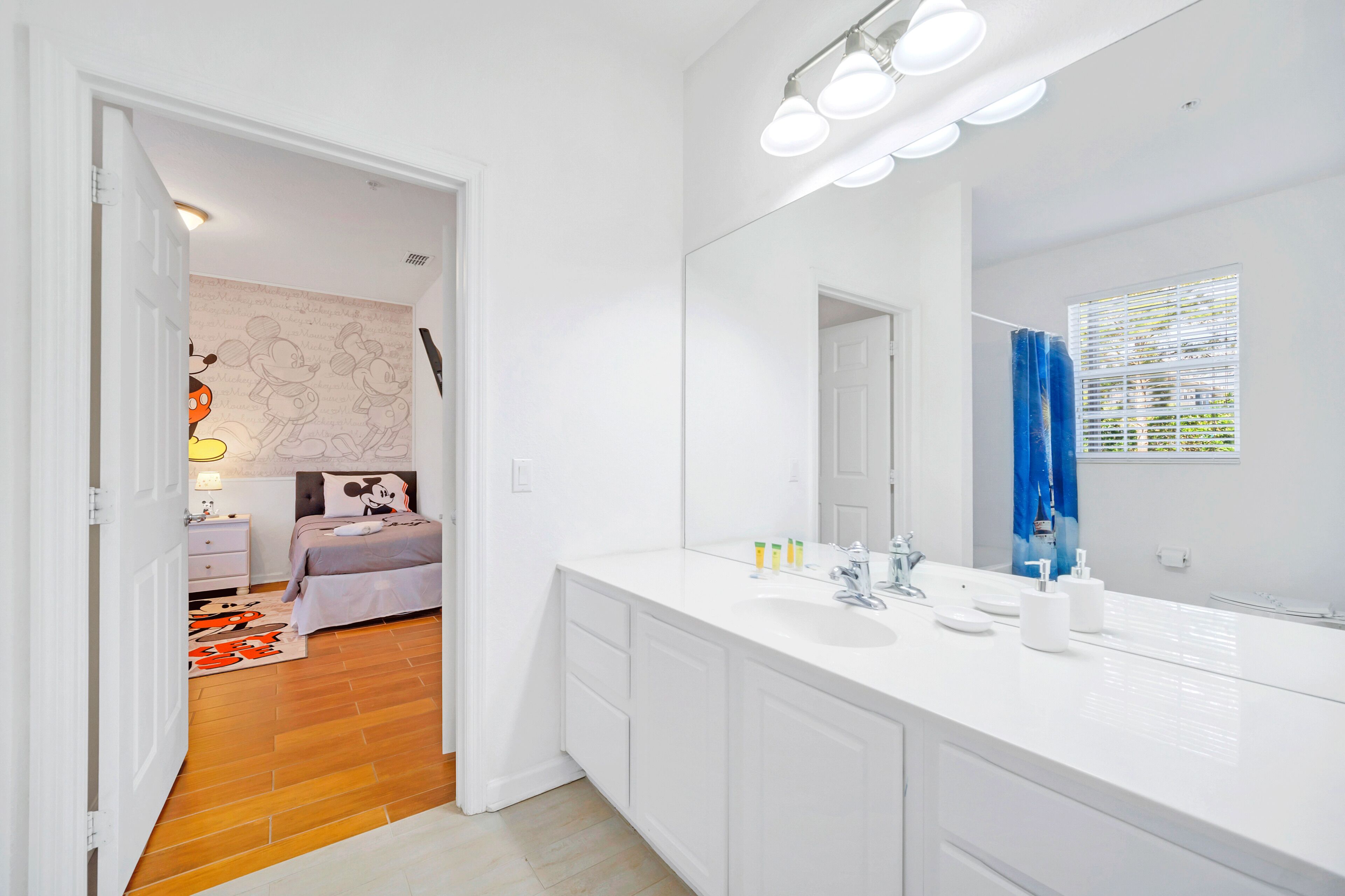 Une salle de bain moderne avec un grand miroir, un meuble-lavabo blanc et un espace douche.