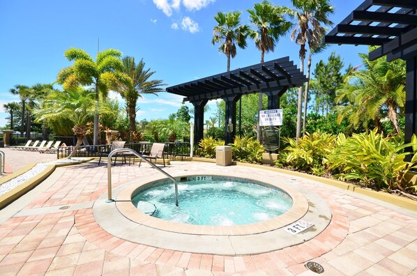 A hot tub area with a pergola, lounge chairs, and palm trees. - Cozy 3BR Apartment Near Disney (Orlando)
