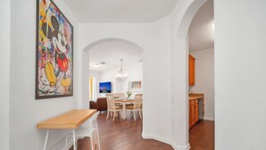 Ein modernes Interieur mit Essbereich, Küche und einem Flur, der in einen weiteren Raum führt.