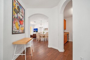 A modern interior with a dining area, kitchen, and a hallway leading to another room. - Cozy 3BR Apartment Near Disney (Orlando)