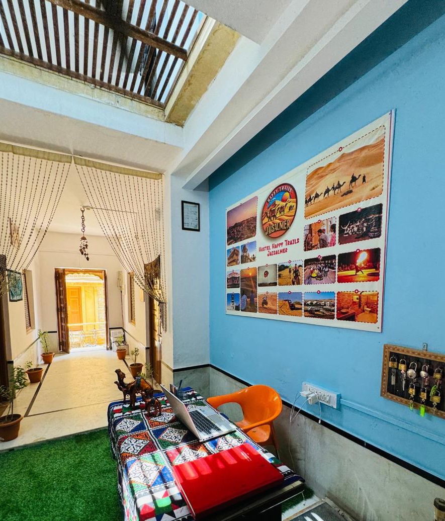 Quarto com cama, escrivaninha, laptop, cadeira e cartaz na parede.