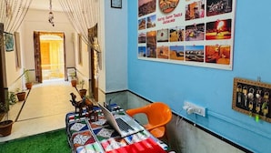 A room with a bed, a laptop, and a wall decorated with photos and a sign. - Happy Trails Jaisalmer (Jaisalmer)