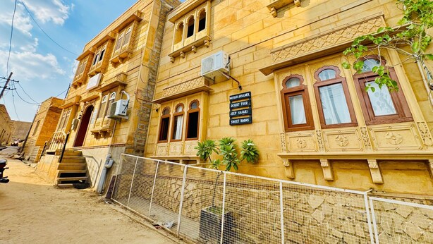 A traditional building with a signboard advertising a desert tour, jeep safari, and sweet rooms. - Happy Trails Jaisalmer (Jaisalmer)