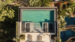 Vista aérea de uma área de piscina moderna com duas espreguiçadeiras e uma piscina pequena.