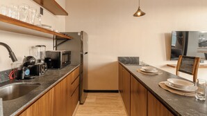 Cozinha moderna com armários de madeira, bancada preta e geladeira embutida.