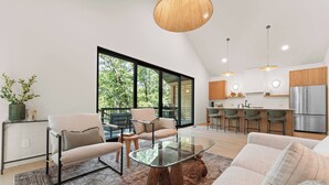 A modern kitchen with a large island, a dining area with a glass table, and a cozy seating area with a sofa and chairs. - Lakefront Wellness Retreat on Table Rock w/ Sauna, Cold Plunge, Hot Tub, Gym (Omaha)