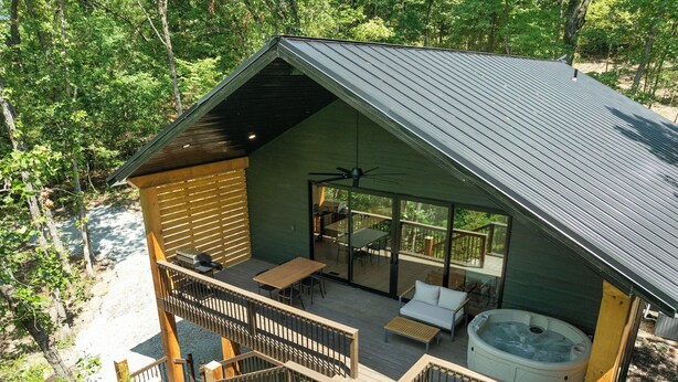 A modern cabin with a deck, a hot tub, and a covered outdoor seating area. - Lakefront Wellness Retreat on Table Rock w/ Sauna, Cold Plunge, Hot Tub, Gym (Omaha)