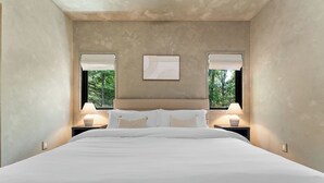 A large bed with white linens, two bedside lamps, and a framed artwork above the bed. - Lakefront Wellness Retreat on Table Rock w/ Sauna, Cold Plunge, Hot Tub, Gym (Omaha)