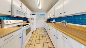 A compact kitchen with white cabinets, a wooden countertop, and a tiled floor. - Beach Access Across the Street, Shared Heated Pool (Corpus Christi)