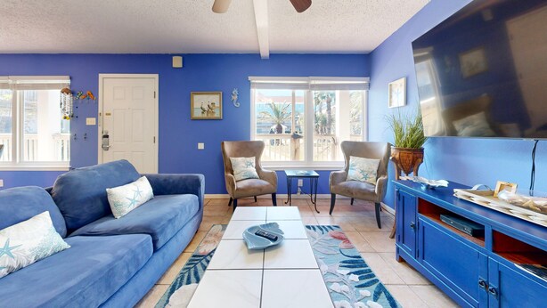 A living room with a blue sofa, two armchairs, a coffee table, and a TV stand. - Beach Access Across the Street, Shared Heated Pool (Corpus Christi)