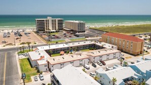 An aerial view of a hotel with multiple buildings, parking lots, and a beach in the background. - Beach Across the Street, Shared Heated Pool, Pet Friendly (Corpus Christi)