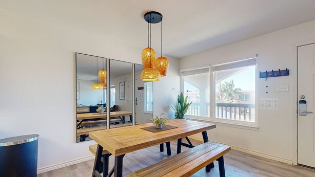 A dining area with a wooden table, benches, and hanging pendant lights.