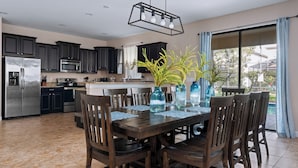 A modern kitchen with dark cabinets, stainless steel appliances, and a dining area with a wooden table and chairs.