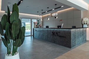 A reception desk with a marble top, a potted plant, and a sign that reads "NO* HOTEL".