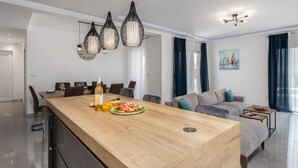Et moderne køkken med en træø, spiseområde med stole, og en sofa i en stue.