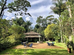 A courtyard with a tiled-roof gazebo, outdoor seating, and lush greenery. - FAZENDA CATUÇABA (São Luiz do Paraitinga)