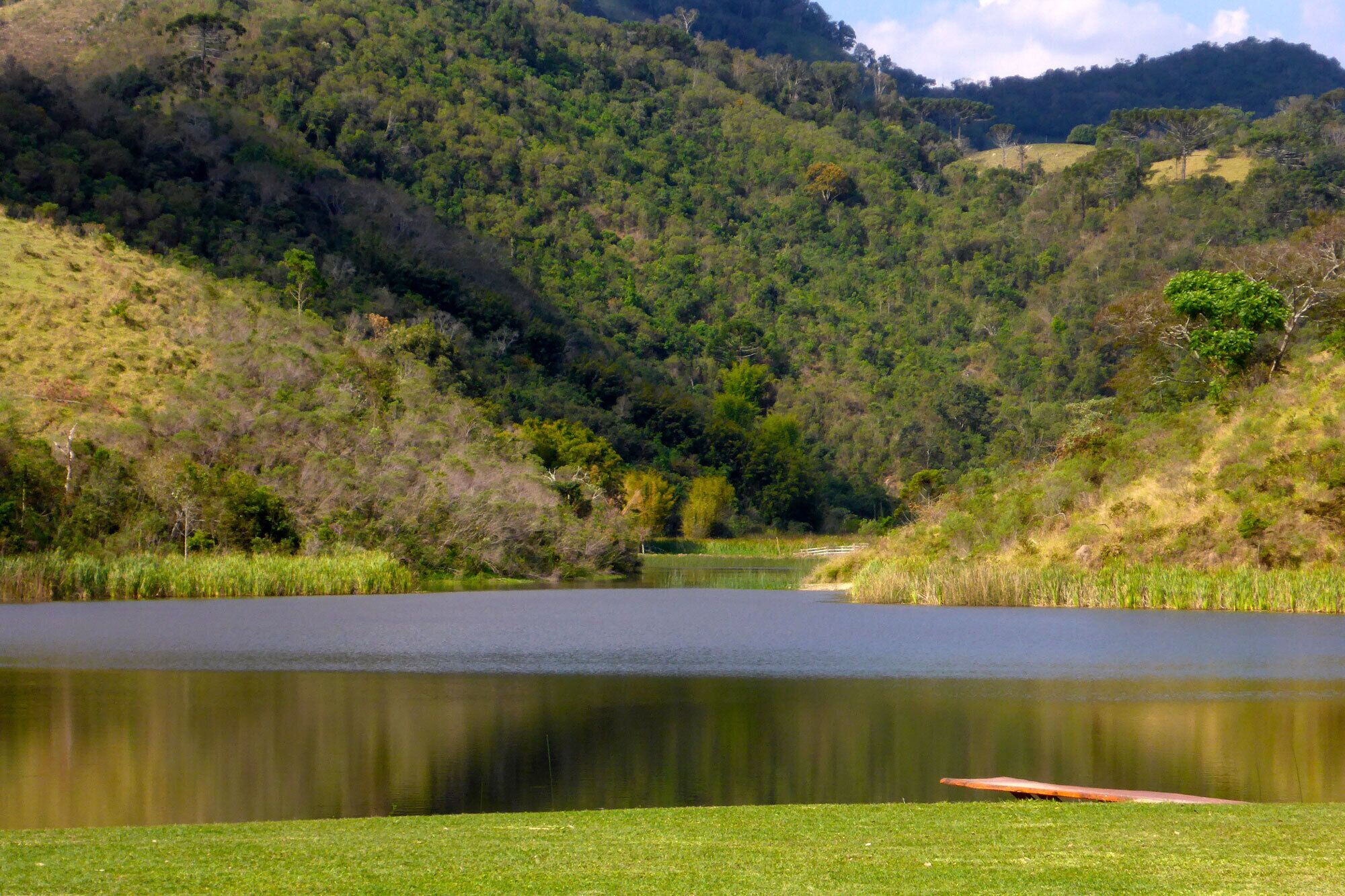 A serene lake surrounded by lush greenery and hills.