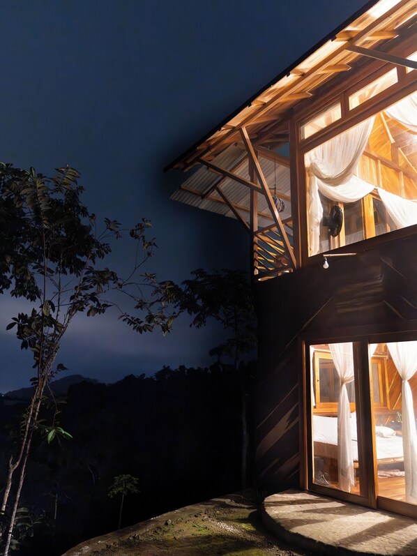 Una casa moderna con un amplio ventanal y un balcón de madera.
