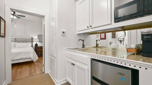 Cocina compacta con armarios blancos, microondas integrado, refrigerador Danby y cafetera.