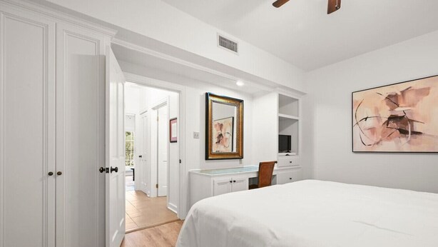 Un dormitorio con una cama grande, un escritorio y una silla. Hay una puerta que da a otra habitación.