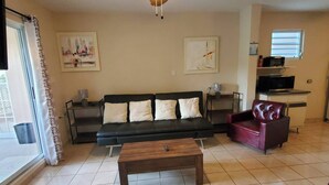 A living room with a ceiling fan, a sofa, a coffee table, and a red armchair.