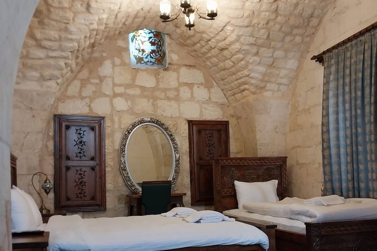 A room with two wooden beds, a large mirror, and a chandelier.