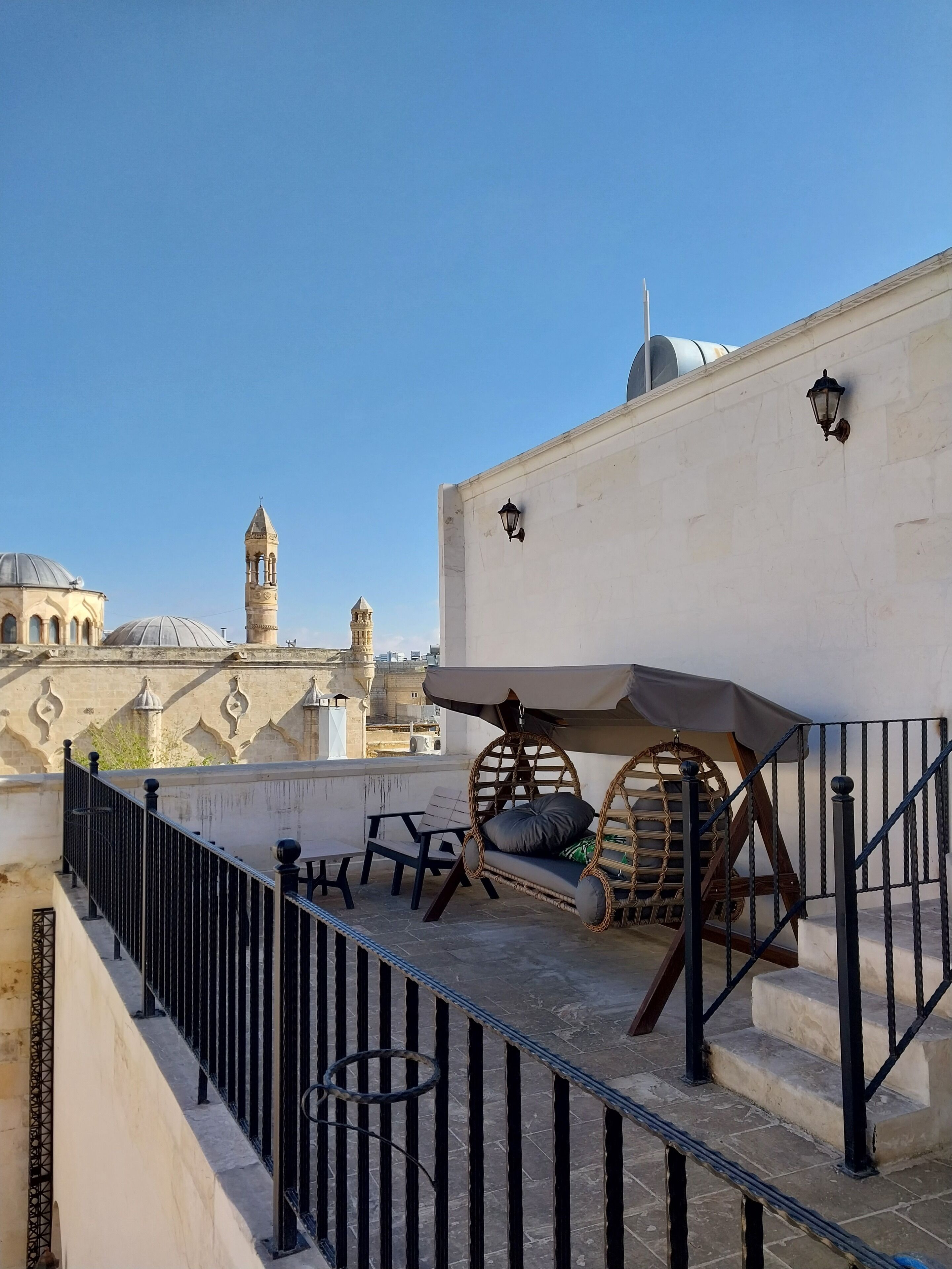 Una terraza en la azotea con vistas a edificios históricos, incluyendo una torre y cúpulas.