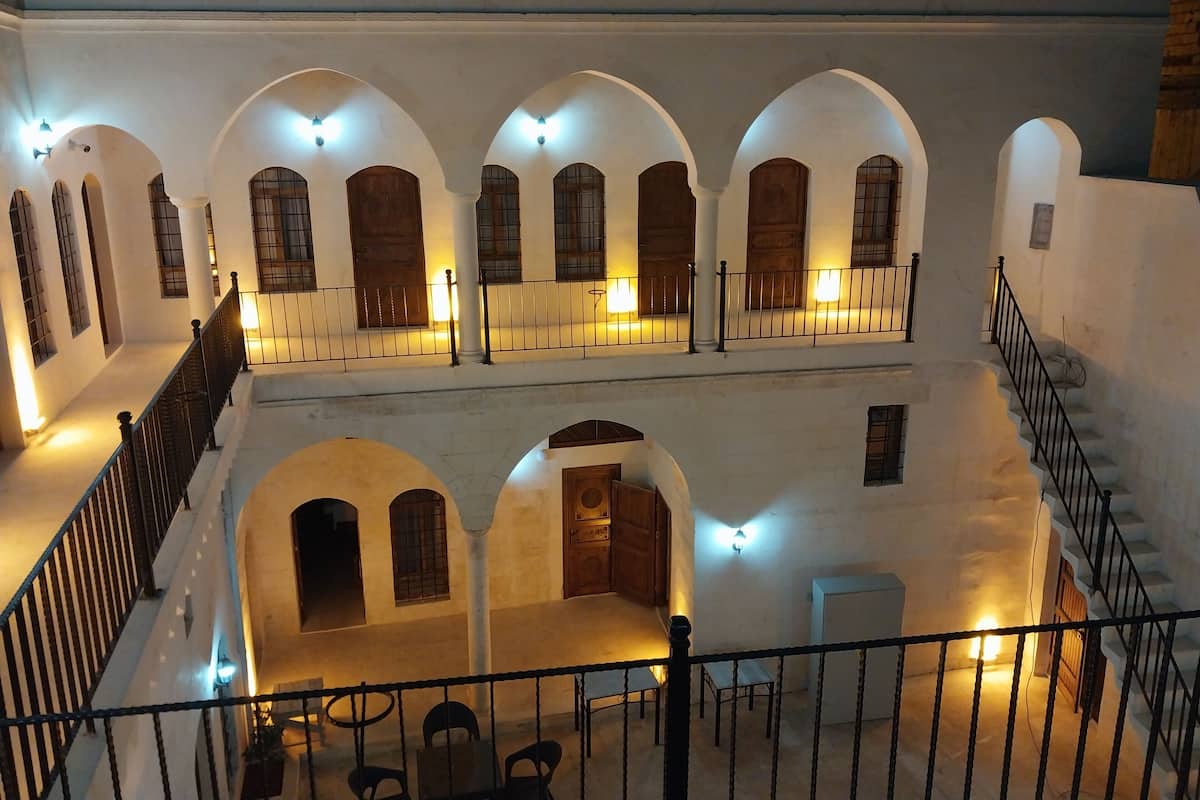 A courtyard with white walls, multiple arches, and wooden doors.