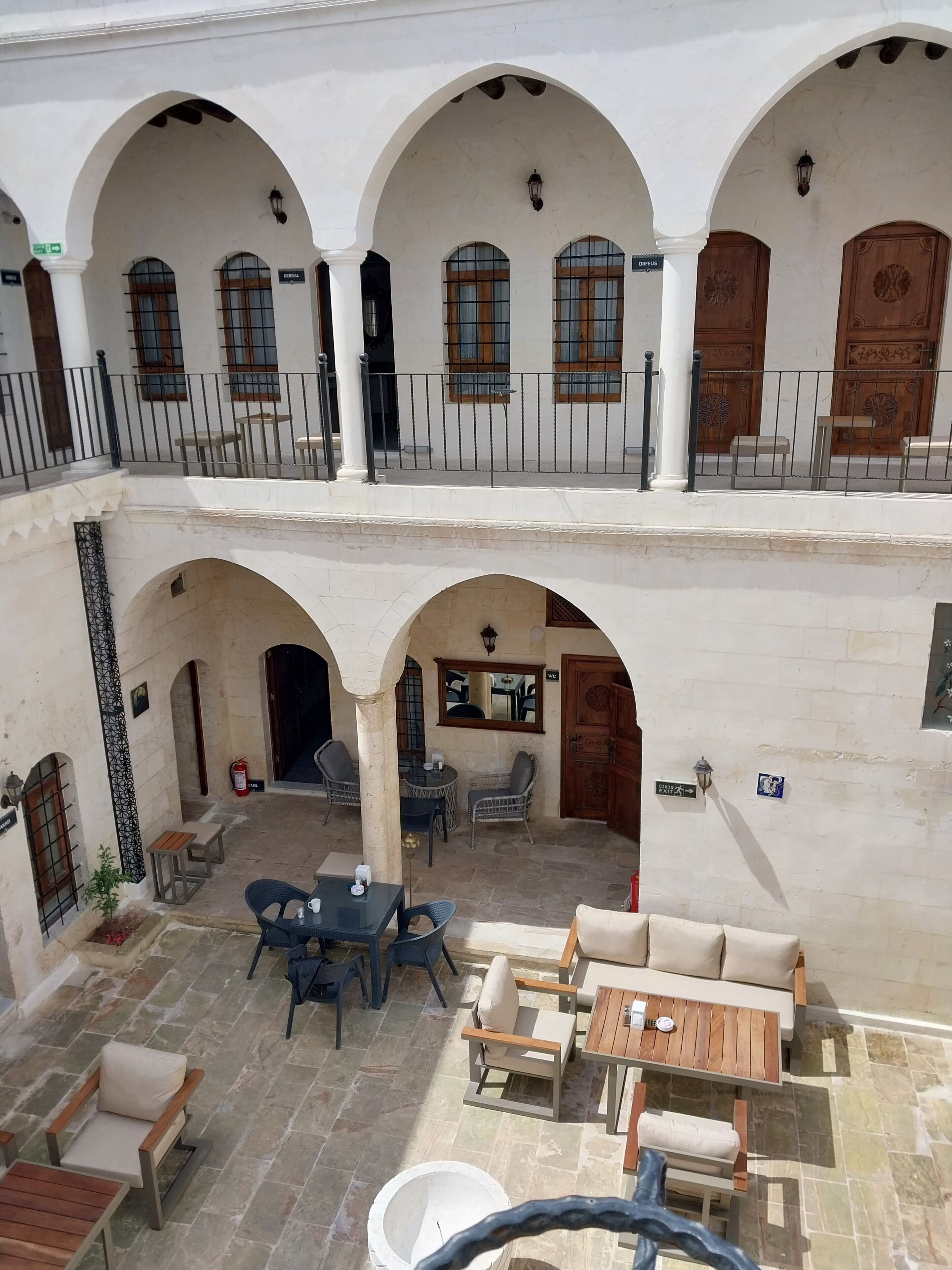A courtyard with outdoor seating, white walls, and wooden doors.