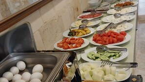Un bufé con distintos alimentos, como huevos, verduras y pan.