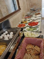 Un bufé con distintos alimentos, como huevos, verduras y pan.
