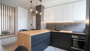 Eine moderne Küche mit einer Holz Arbeitsplatte, dunklen Schränken und einem eingebauten Backofen.