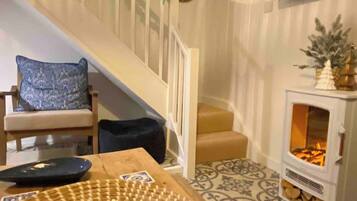 A staircase with a railing, a patterned floor, a table with a decorative centerpiece, a chair, and a fireplace with a mantel.