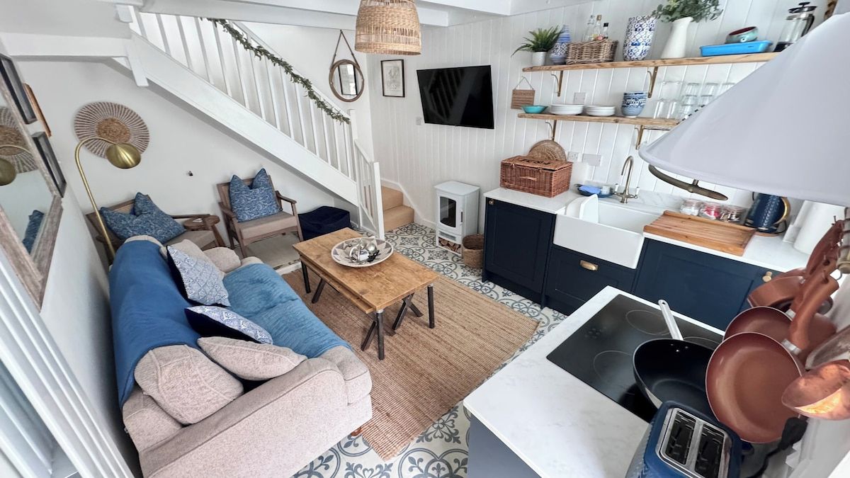 Una cocina moderna con comedor, una escalera y un televisor montado en la pared.