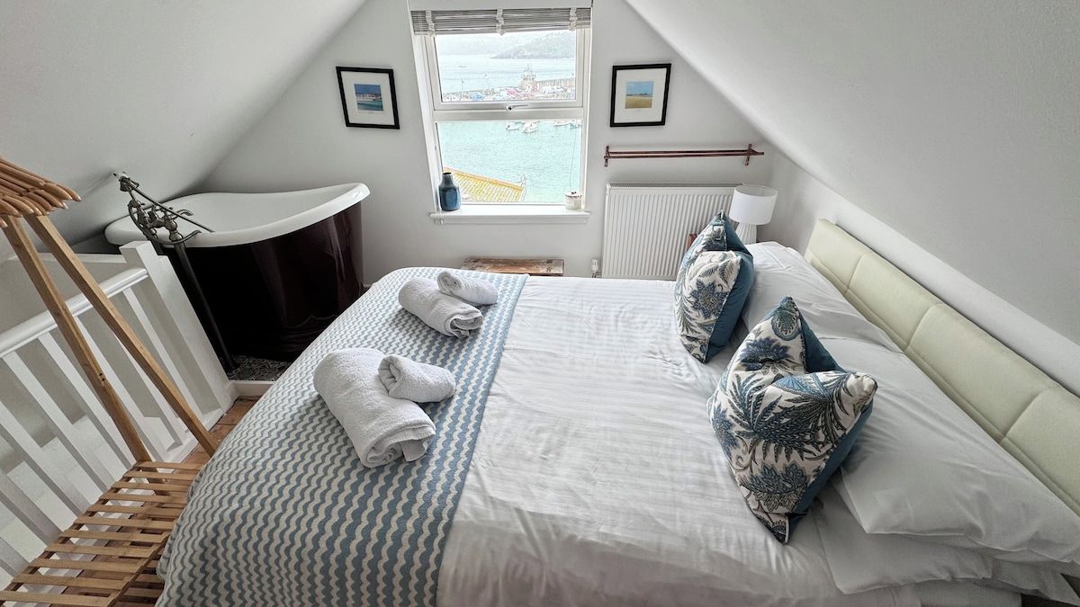 Ein Schlafzimmer mit einem Bett, einem Fenster mit Blick, einem Heizkörper und einer Holzecke.
