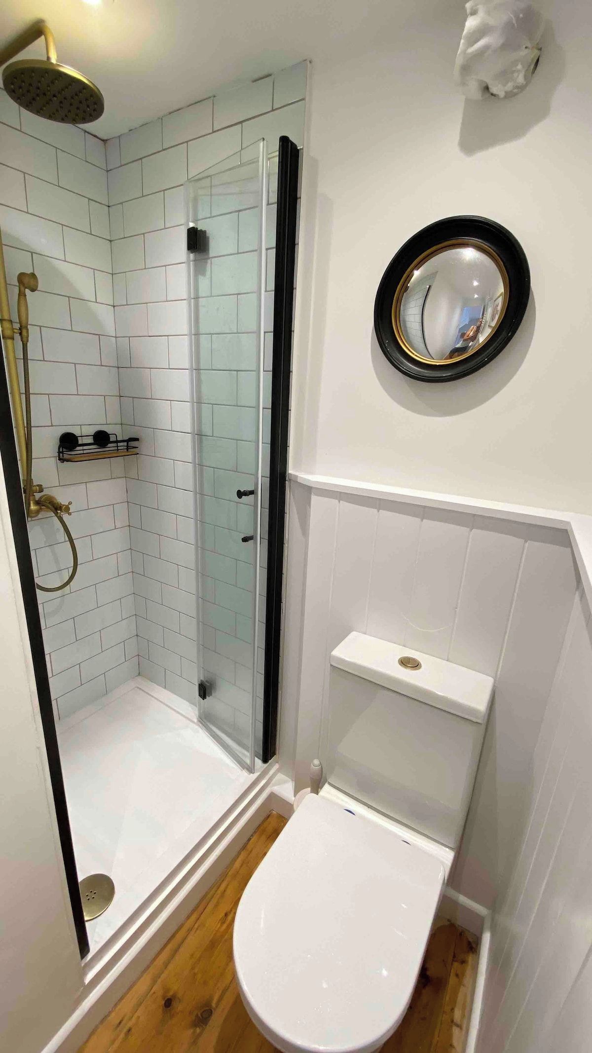 Un baño con ducha, inodoro y un espejo en la pared.