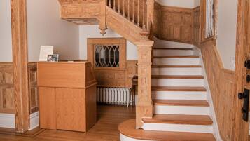 A wooden staircase with a handrail and a landing area with a radiator.
