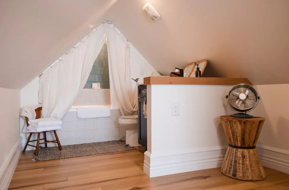 A small, cozy bathroom with a shower, a toilet, a vanity, and a fan.